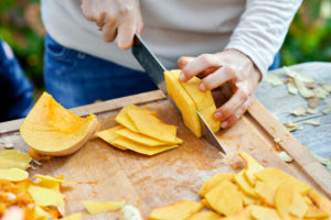 Half a Hokkaido pumpkin and pumpkin wedges, split on a wooden board with a chef's knife Half a Hokkaido pumpkin and pumpkin wedges, split on a wooden board with a chef's knife